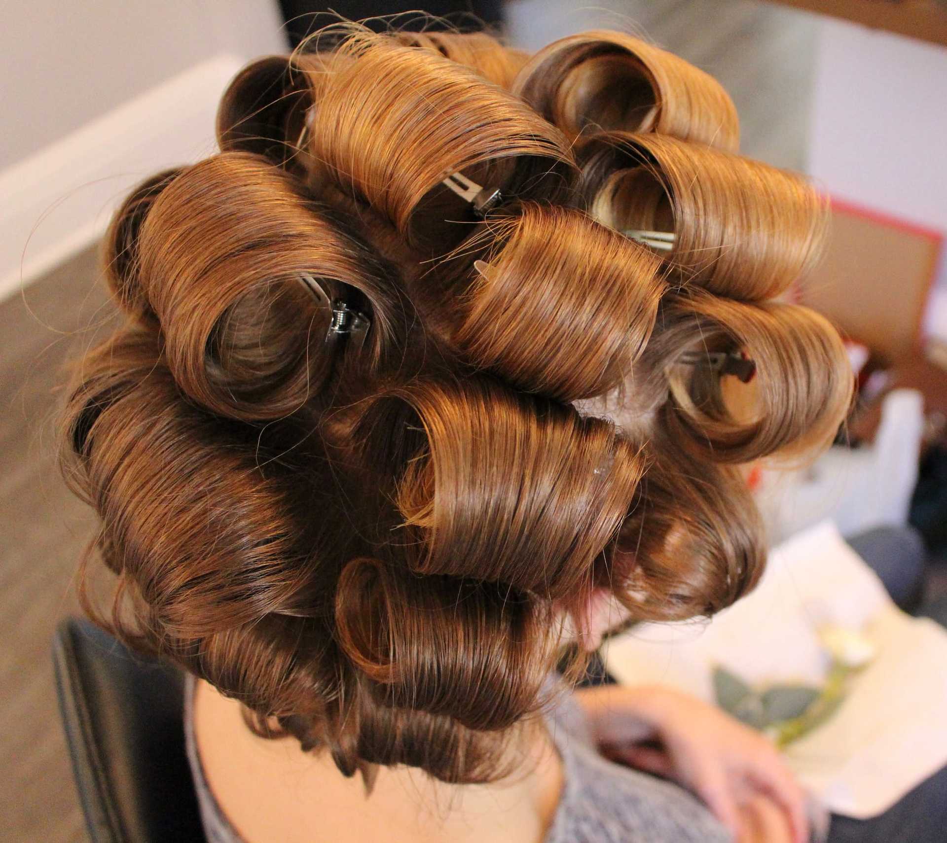 Hair with brown curlers in a salon setting, viewed from above.