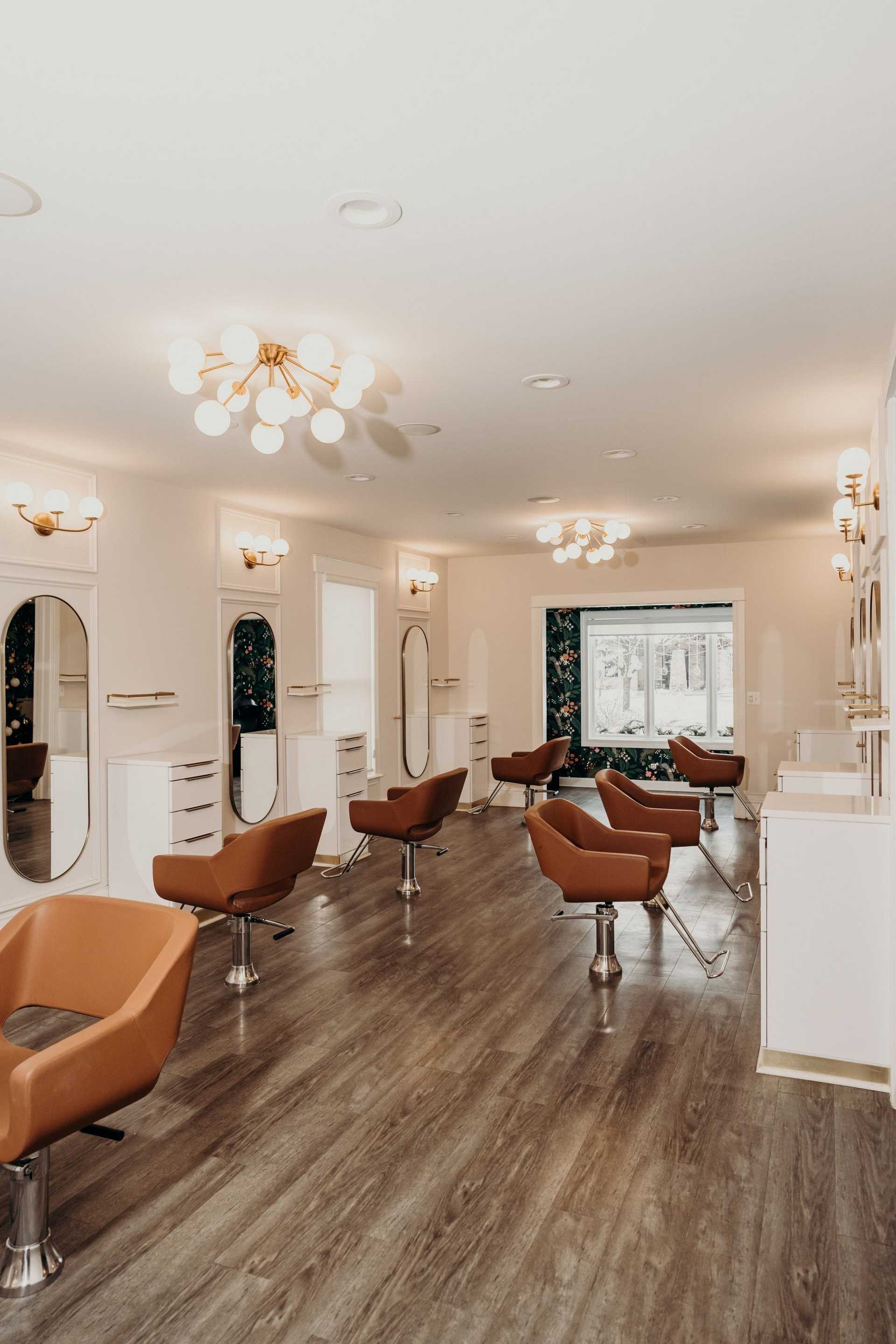 Modern hair salon with brown chairs and elegant lighting.
